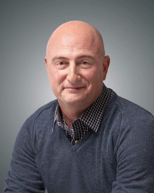 A professional headshot of Ryan Barr on a grey and white gradient background.