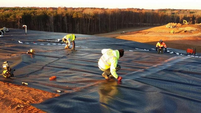 A photograph of workers installing ClosureTurf over a landfill