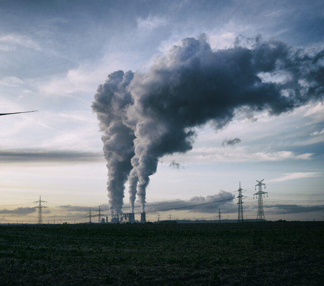 A coal burning power plant with pollution and electricity pylons in the background.