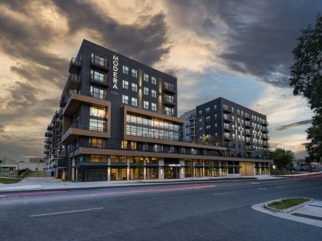 An exterior, nighttime photograph of Modera LoSo, a multi-story apartment complex