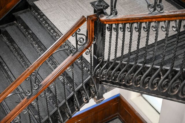 A detail photograph of highly intricate iron stairs and wooden railings.
