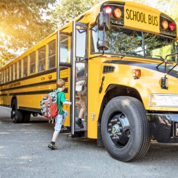 A group of young children getting on the school bus