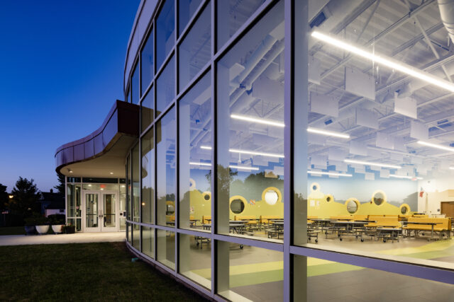 Exterior of K-12 school building looking into cafeteria