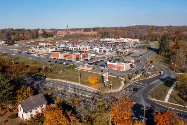 An aerial photograph of the Hudson Heritage plaza including the entry to Route 9 and remains of the former Hudson River Psychiatric Center in the background