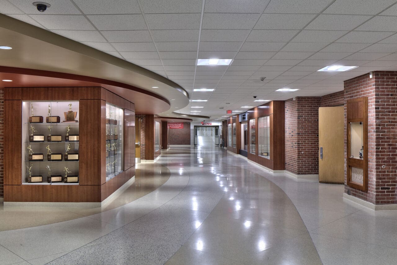 A photograph of a school hallway lined with display cases showcasing trophies.