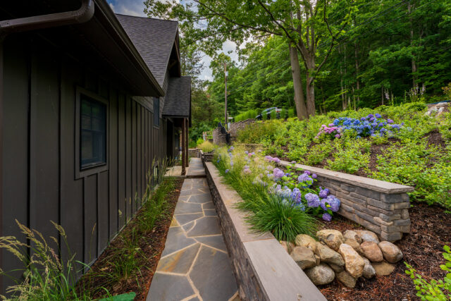 A photograph of tiered walls, stonework, and plantings adjacent to a home