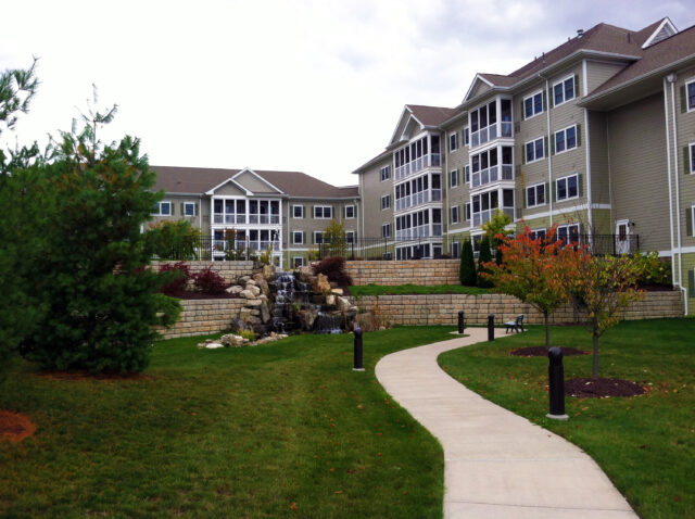 A photograph of landscaping and a small waterfall in front of multi-family housing