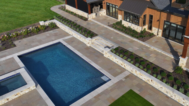 A photo of a stonework around an in-ground pool in the outdoor living space of a single-family home.