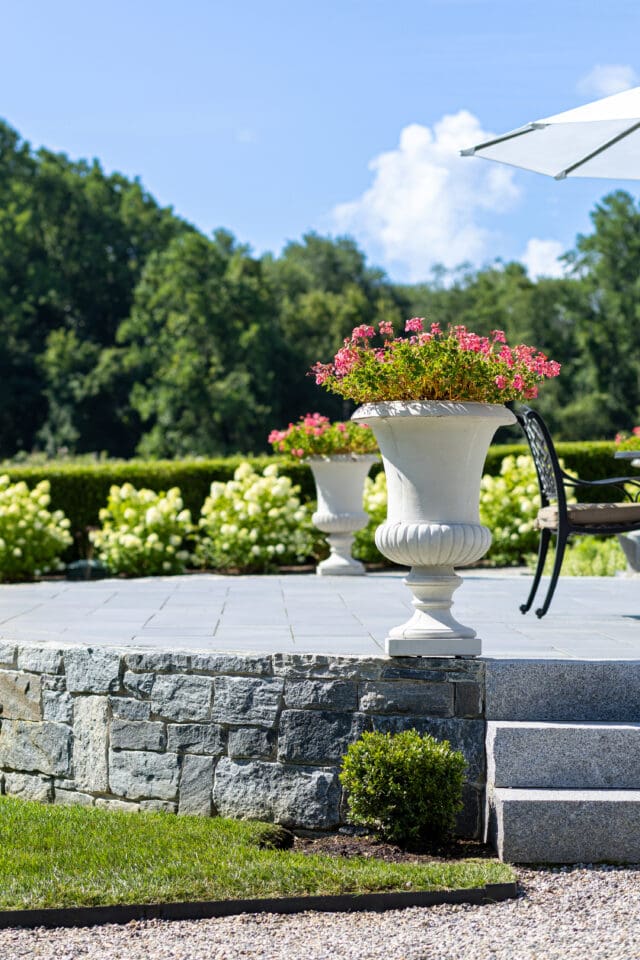 A photograph of a stone patio with stone vases of flowers at Smith Farm Gardens venue in East Haddam, CT