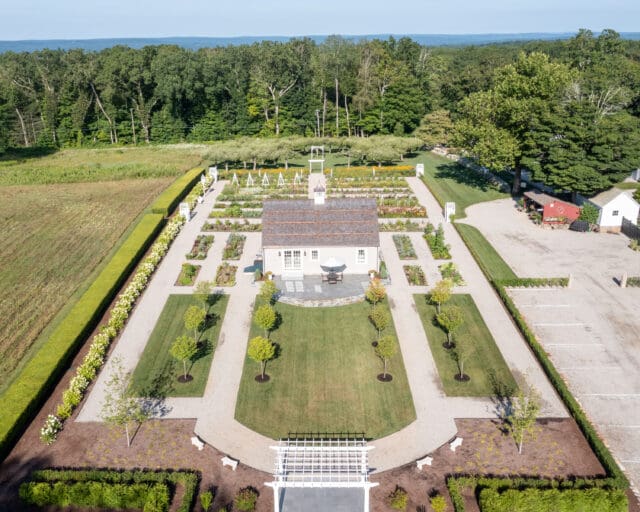 An aerial photograph of a cottage at the center of gardens and cherry trees at Smith Farm Gardens venue in East Haddam, CT