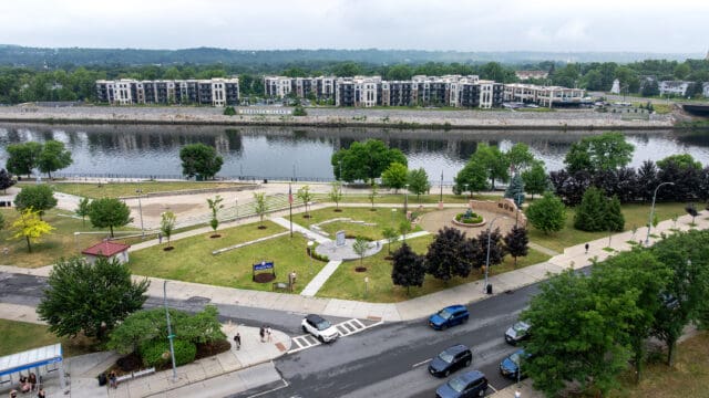 An aerial photograph of the William C. Chamberlain Riverfront Park, which shows two monuments, walking paths, and landscaping. with the Hudson River in the background.