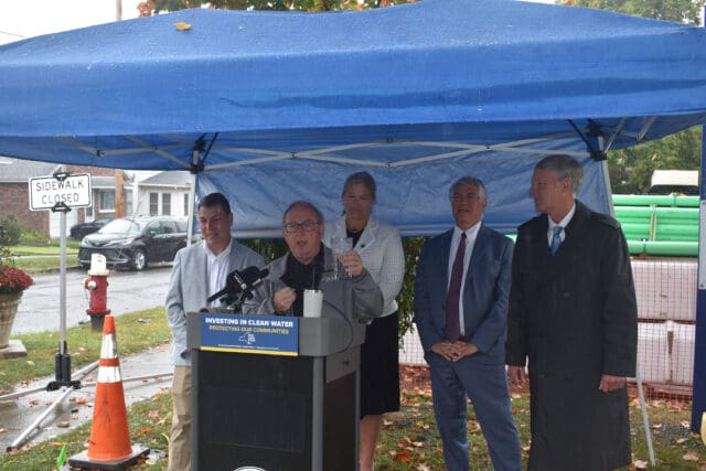 A photograph of New York State Health Commissioner Dr. James McDonald speaking at a podium under a tent in front of four other people