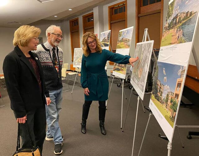 A photograph of one person presenting a board to two people