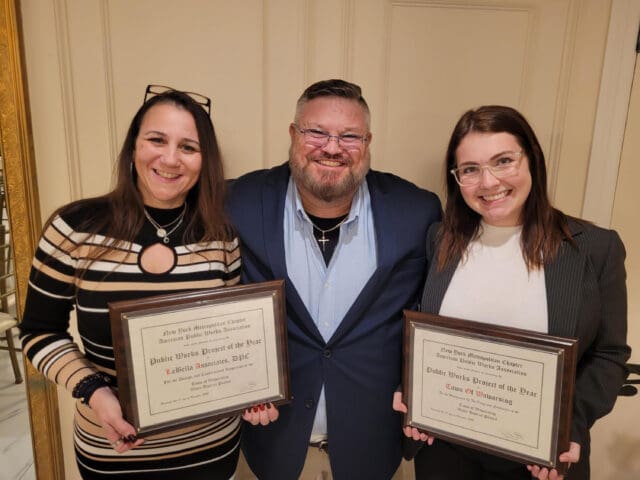 A photograph of three people holding awards