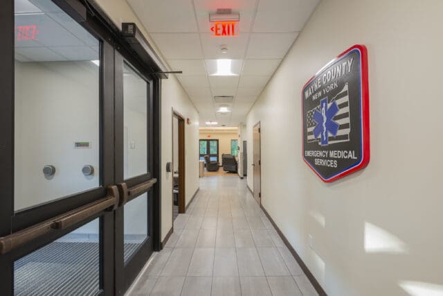A photograph of a main entrance hallway with double doors and a company emblem on the wall.