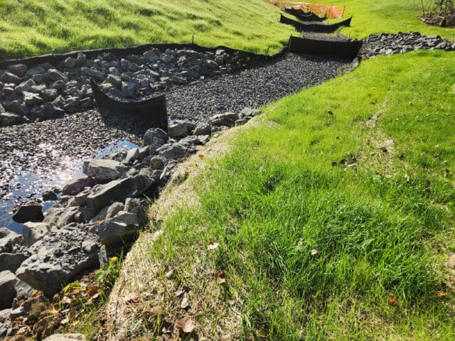 A photograph of stormwater management between two grassy inclines.