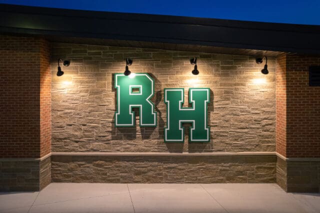 A photograph of the side of a building in the evening with the letters HR lit up.
