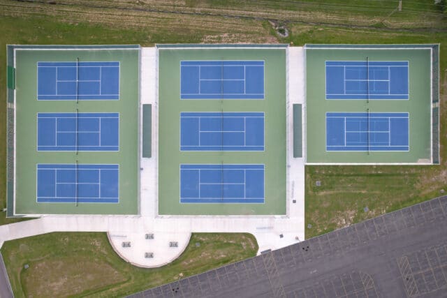 An aerial photograph of eight blue tennis courts