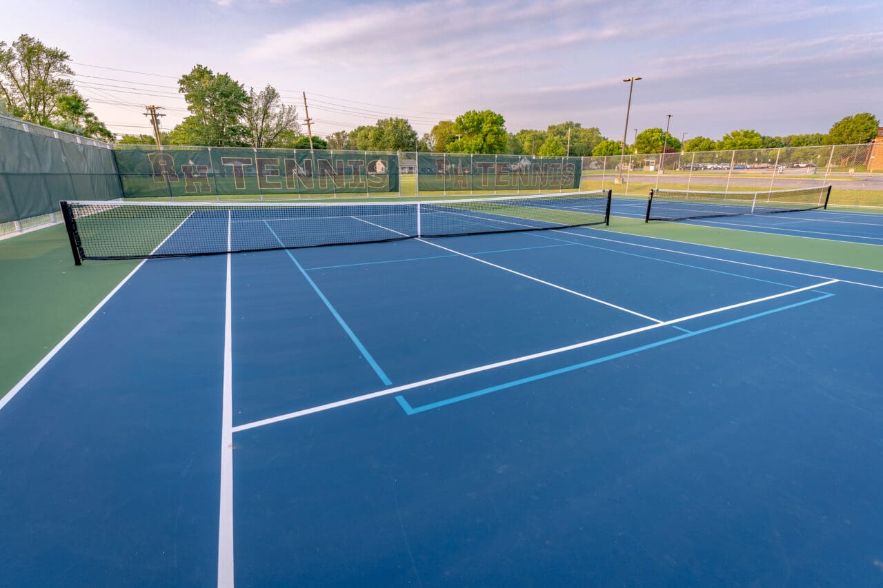 A photograph of a blue tennis court with additional lines for a pickleball court