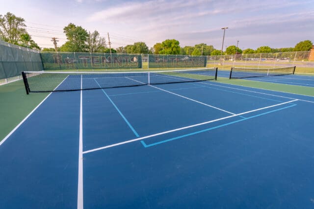 A photograph of a blue tennis court with additional lines for a pickleball court