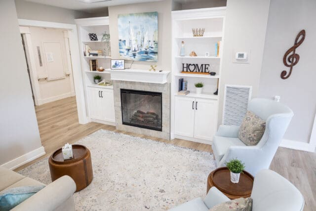 A photograph of a modern living area with a fireplace, white and brown leather furnishings, and tasteful decor.