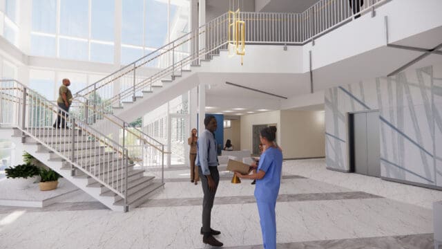 A simulation of the lobby of the Nursing Education Center at Aiken Technical College. An open staircase leads to the second floor. Elevators are visible. The floor and lighting fixture are modern. People are milling about.