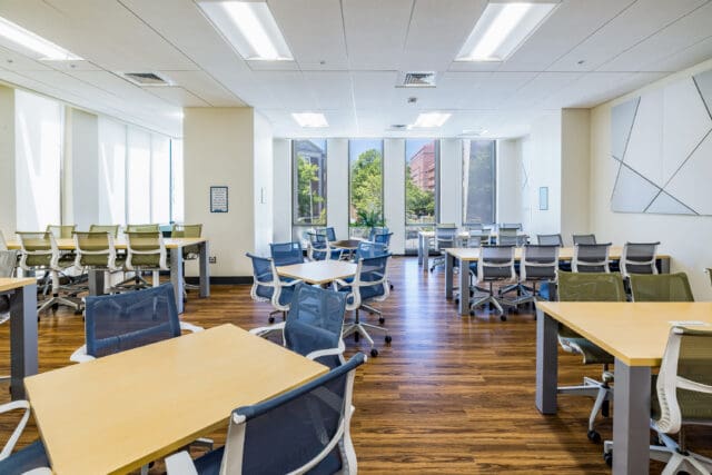 A photograph of a room with many tables and chairs in various clusters spread throughout the space.