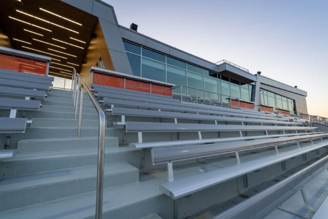 A photograph of a stadium with bleacher seating. The structure has sharp, unique angles.
