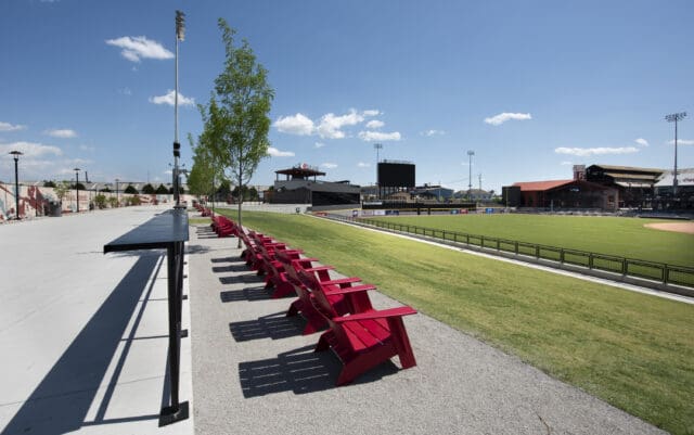 A photograph of a row of red chairs in the outfield of a baseball stadium.