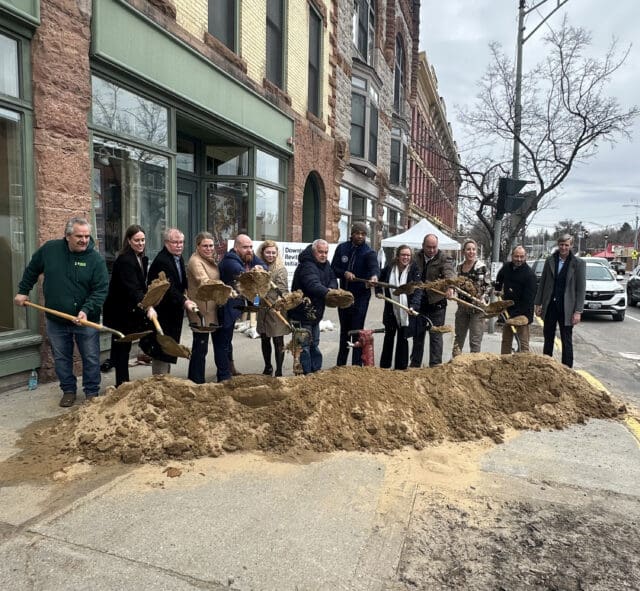 A photograph of a ground of people with shovels throwing dirt at a groundbreaking.