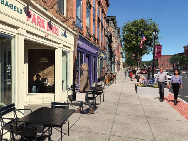 A photo-realistic rendering of a downtown sidewalk with cafe seating and storefronts.