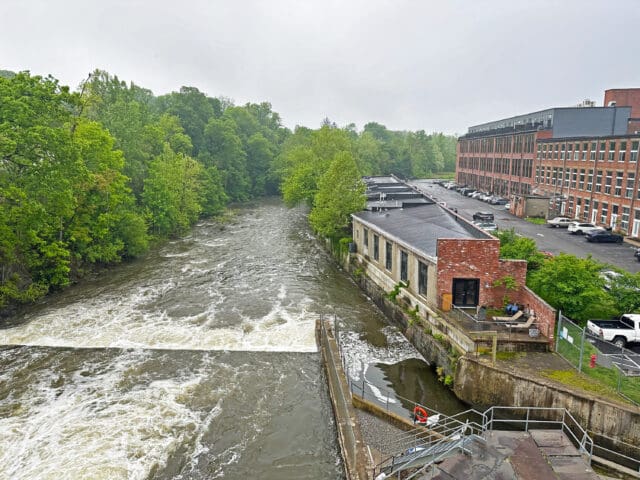 A photograph of a dam adjacent to brick buildings