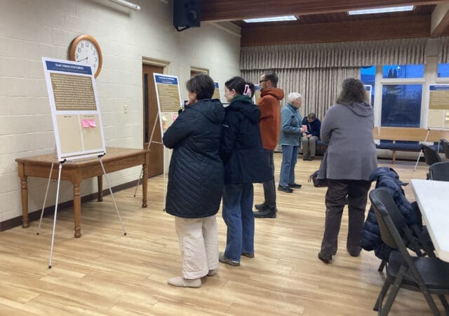 Photograph of multiple people looking at posterboards on easels.