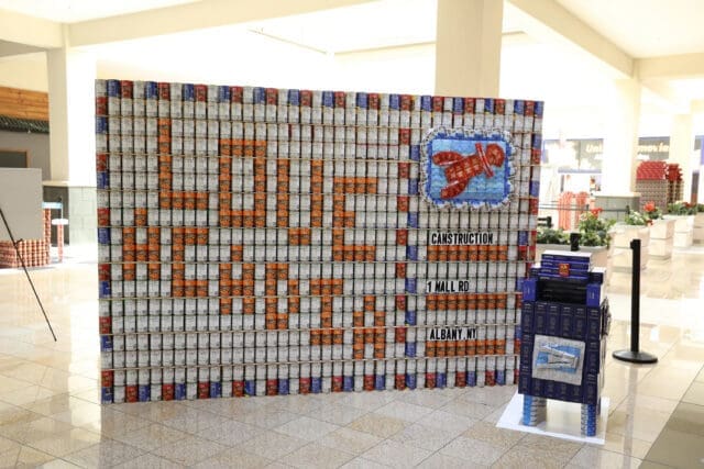 A photograph of a structure made out of canned vegetables, rice, and dish soap. It looks like a postcard that says 
