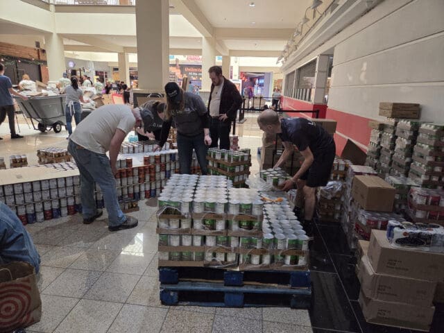A photograph of people unpacking canned goods.