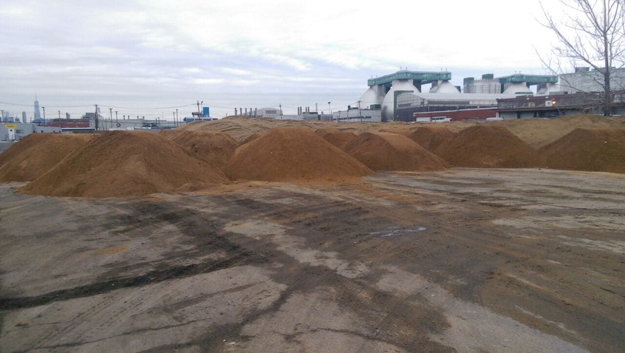 A photograph of a site that appears vacant with multiple piles of soil.