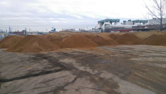 A photograph of a site that appears vacant with multiple piles of soil.