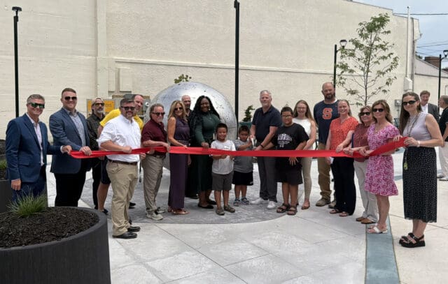 A photograph of a line of people cutting a red ribbon.