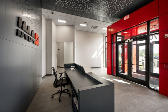 A photograph at the front desk of a building. On the wall is a graphic loco that says IMA.
