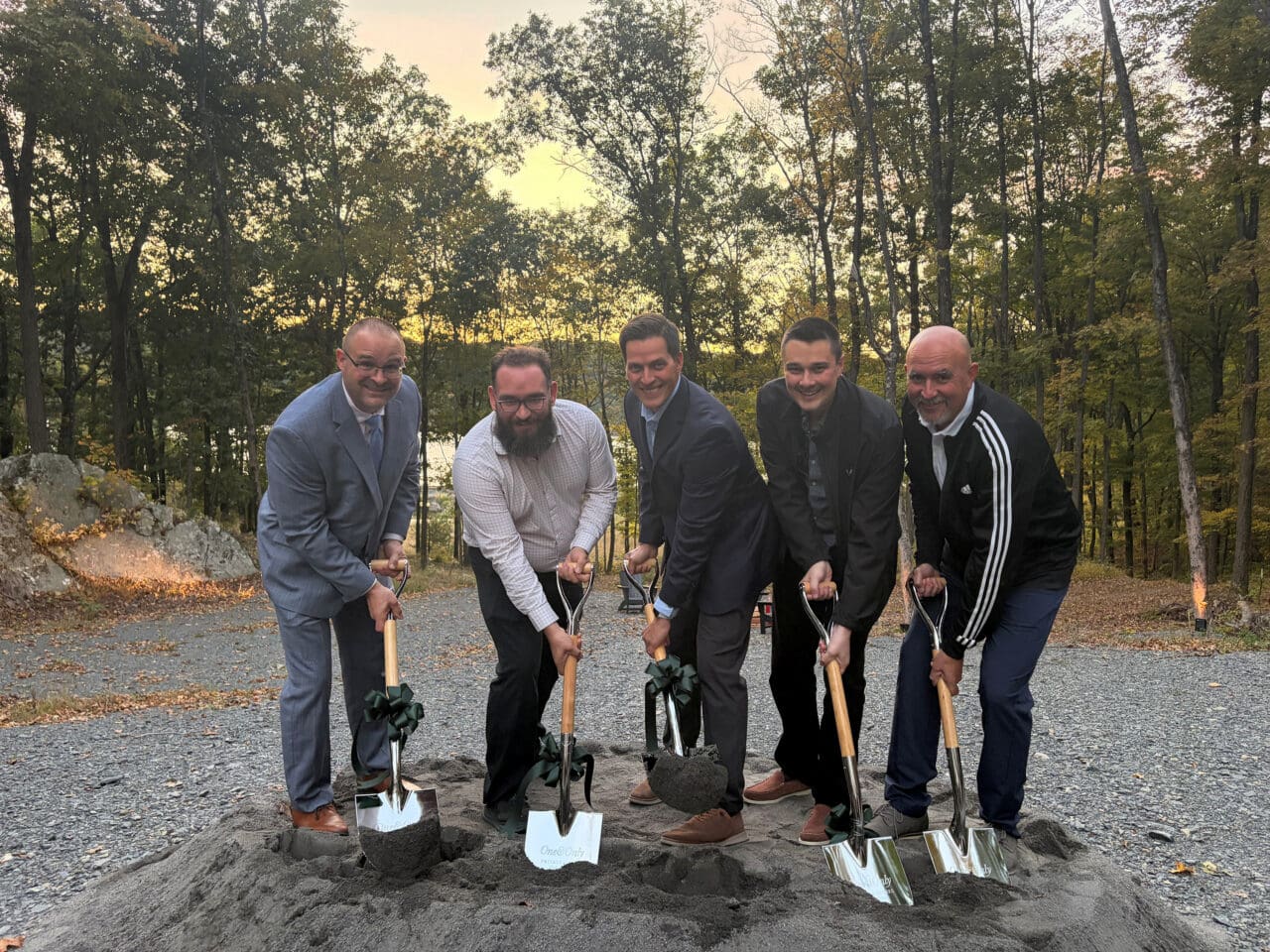 A photograph of five people holding shovels to the ground for a groundbreaking